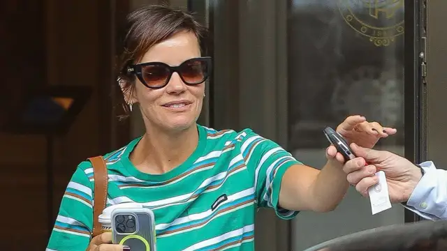 Allen wears a stripy T-shirt and Prada sunglasses while on the beach